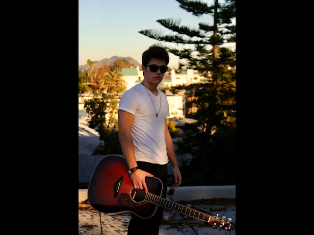 Julius Cole Rassin with sunglasses and guitar at sunset