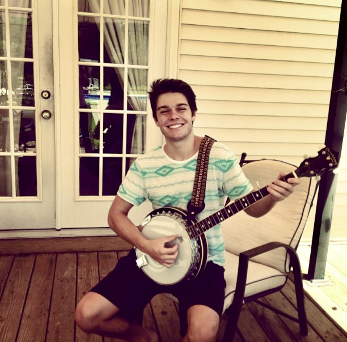 Julius Cole Rassin smiling with a banjo on a porch