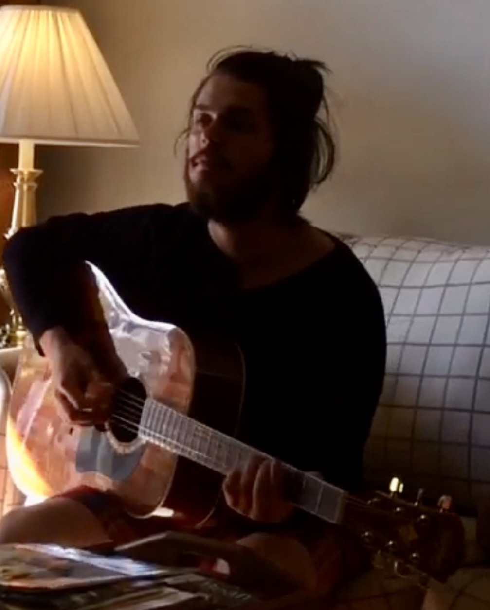 Julius Cole Rassin with long hair, playing acoustic guitar
