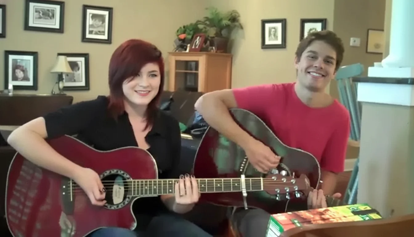 Cole and his friend Hannah Brown playing acoustic guitars together in a living room, both smiling