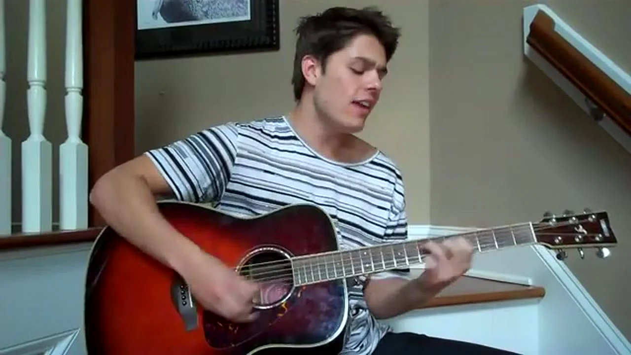 Cole in a striped tee, singing Ocean with his acoustic guitar
