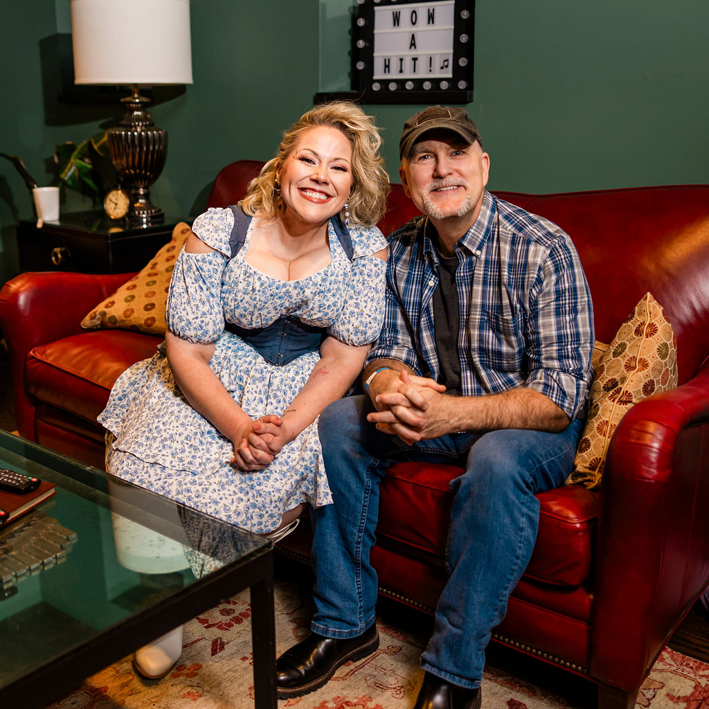 Heidi Parton with a companion posing on a couch beneath a 'WOW A HIT' sign at Franklin Theatre, 2025